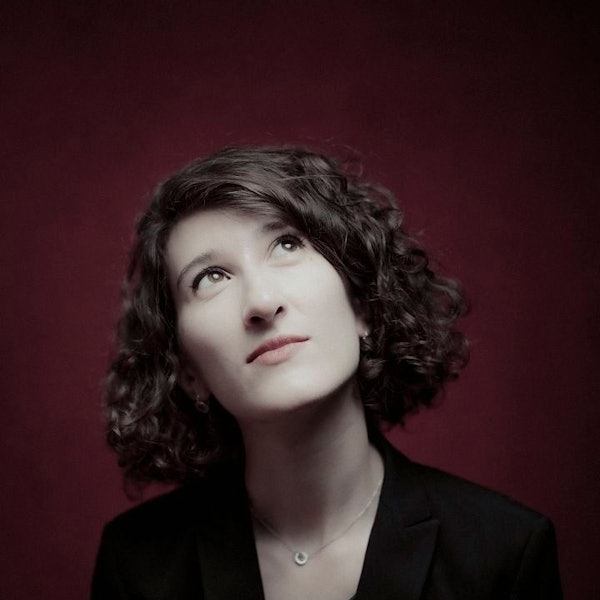 Das Bild zeigt das Gesicht der Pianistin Nathalia Milstein. Sie hat braunes, lockiges Haar und trägt schwarze Kleidung.
