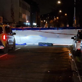 Eine abgesperrte Straße in der Nacht, davor steht ein Polizeiwagen.