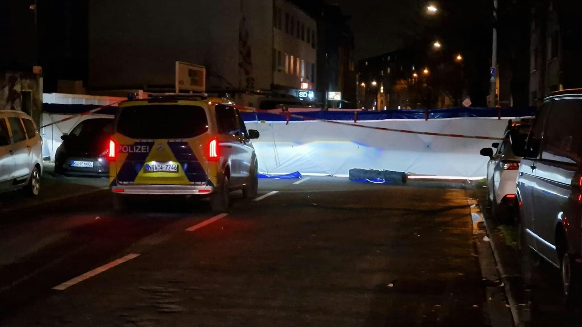 Eine abgesperrte Straße in der Nacht, davor steht ein Polizeiwagen.