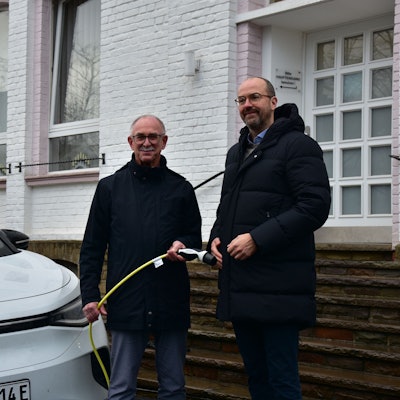 Bürgermeister steht neben einem E-Auto und hält das Ladekabel in der Hand, neben ihm steht der Rhenag-Vorstand.