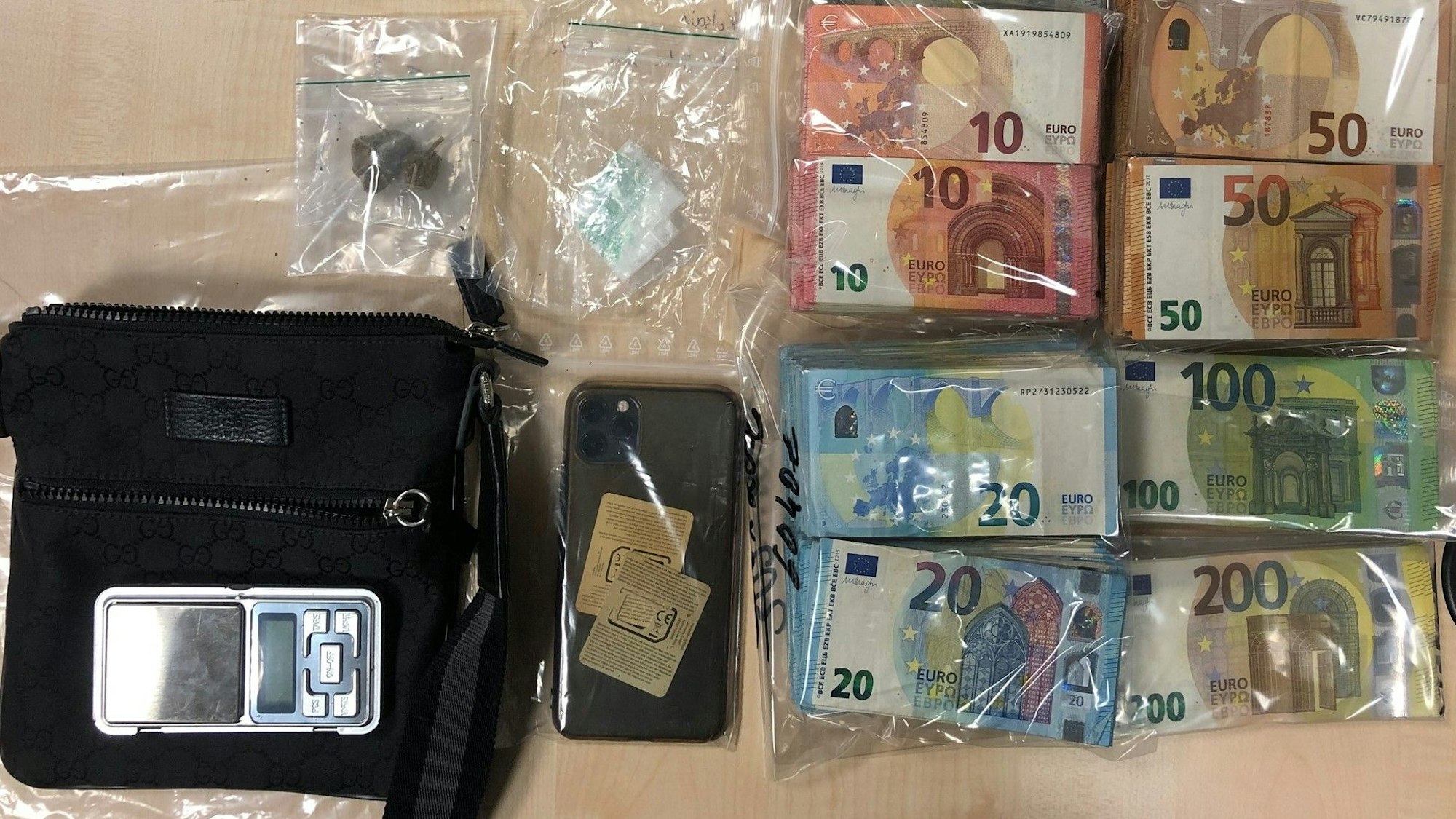 Bargeld in Tüten, ein Handy, und Drogenpäckchen liegen auf einem Tisch