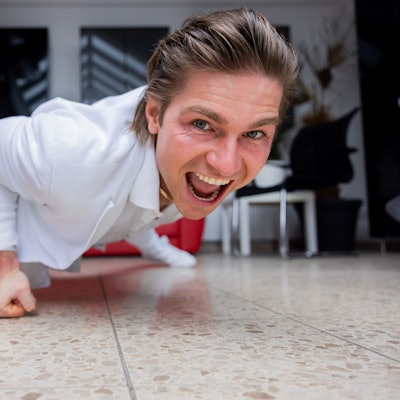 Der Influencer und Webvideoproduzent Jeremy Fragrance macht auf dem Boden seines Hauses einarmige Liegestütze und schaut dabei in die Kamera.