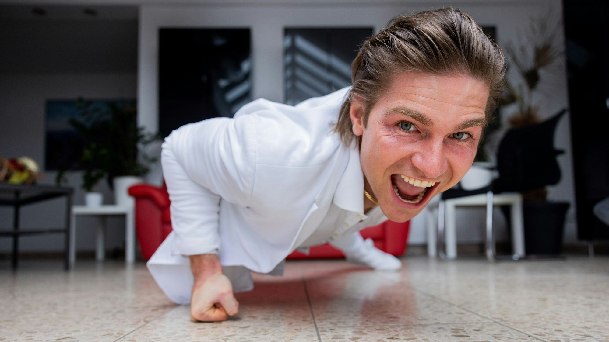 Der Influencer und Webvideoproduzent Jeremy Fragrance macht auf dem Boden seines Hauses einarmige Liegestütze und schaut dabei in die Kamera.