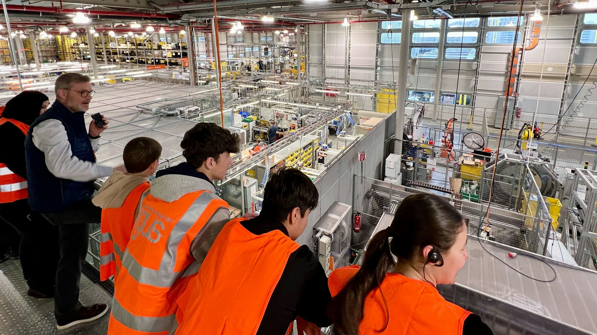 Igus-Mitarbeiter Felix Franke führt die Schülerinnen und Schüler der Kopernikushauptschule durch die Firma am Standort Porz-Lind.