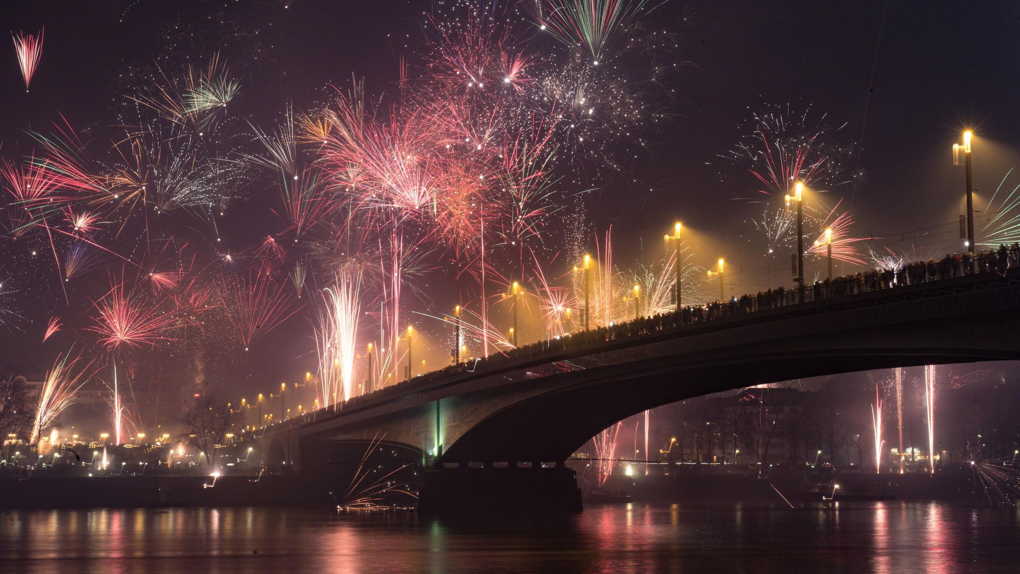 Die Kennedybrücke in Bonn an Silvester aus der Untenansicht mitsamt Rhein davor. Feuerwerk erleuchtet den dunklen Nachthimmel.