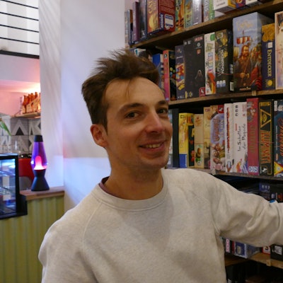 Ein Mann steht an einem Regal mit Spielen.