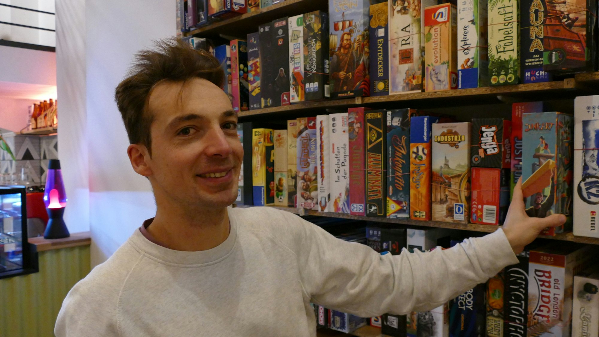 Ein Mann steht an einem Regal mit Spielen.