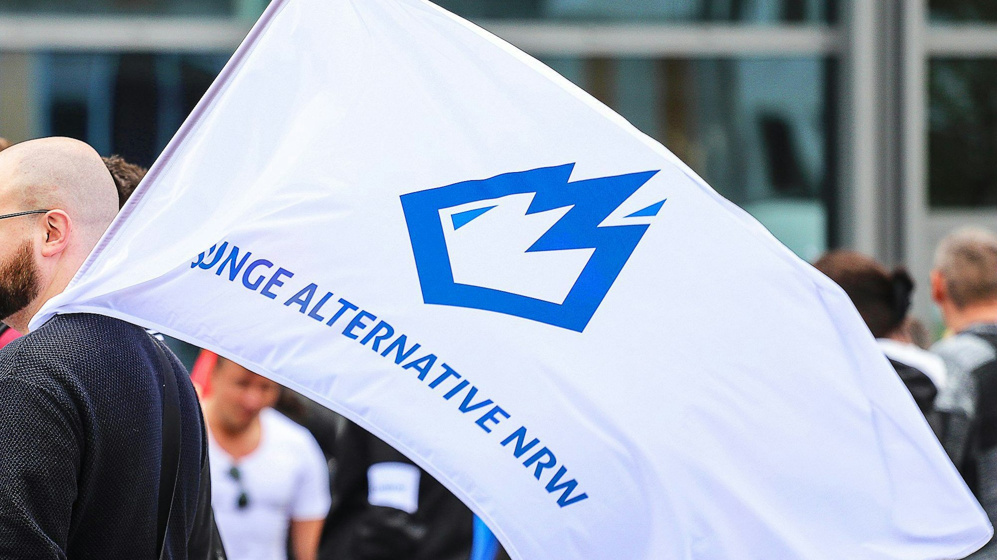 Demo in Dortmund: Ein Mitglied der Jungen Alternative (JA), Jugendorganisation der AfD, trägt auf einer Wahlkampfveranstaltung eine Fahne mit dem Logo der Organisation. (Archivbild)