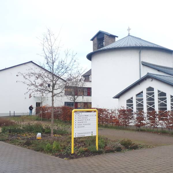 Ein weißes Kirchengebäude mit einem gelben Wegweiser im Vordergrund