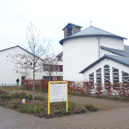 Ein weißes Kirchengebäude mit einem gelben Wegweiser im Vordergrund