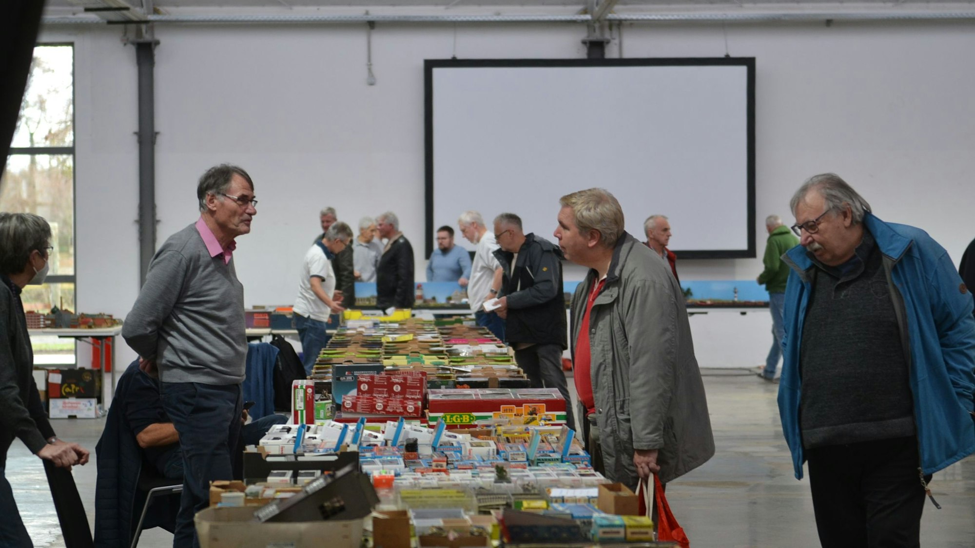 Modellbahnfreunde stehen an einem Tisch und unterhalten sich.