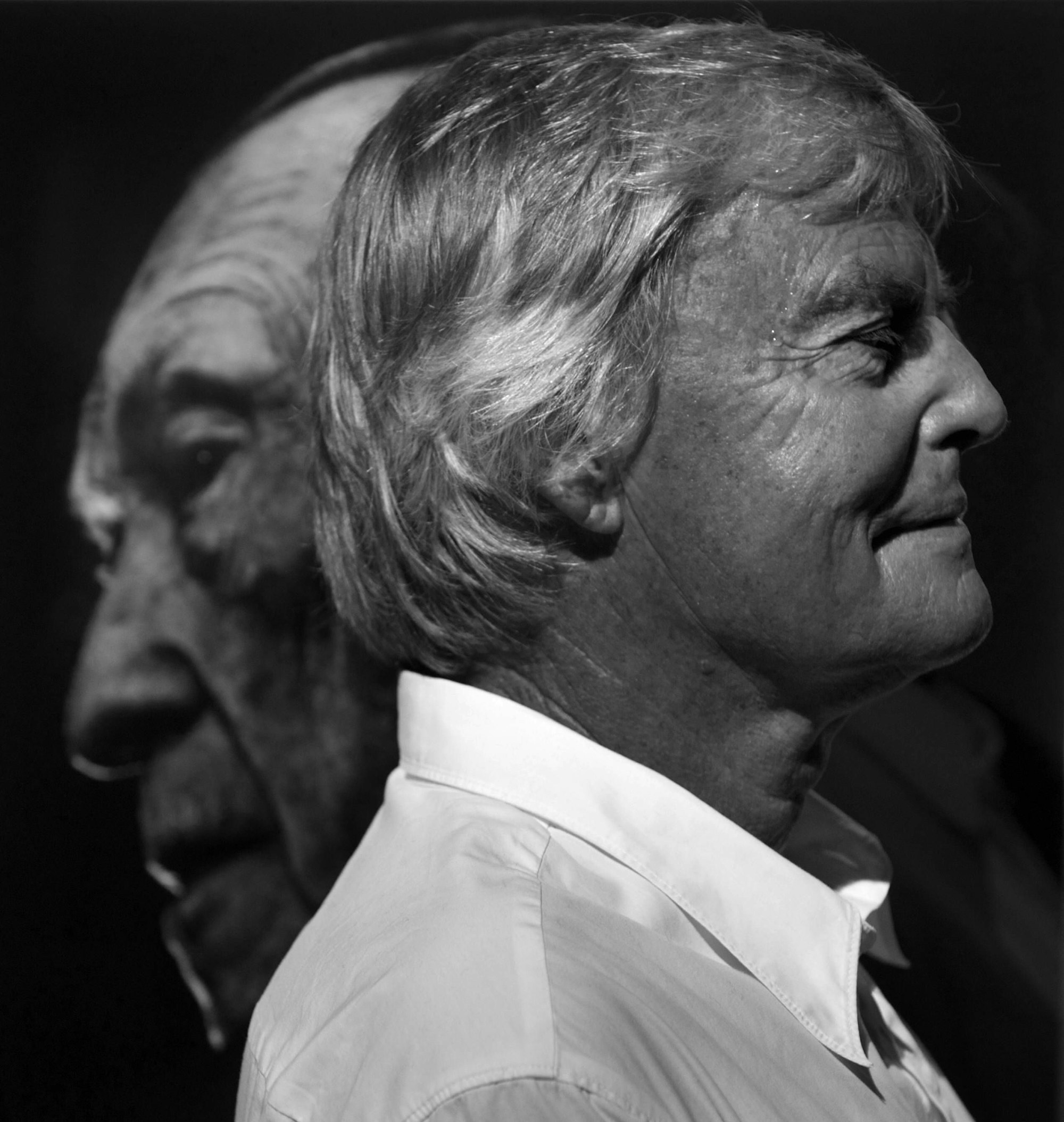 Konrad R. Müller steht seitlich vor einer Aufnahme von Konrad Adenauer.