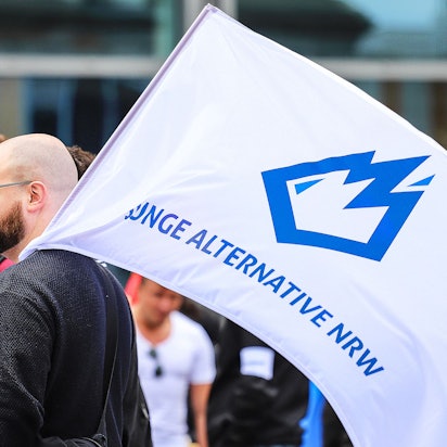 Ein Mitglied der «Jungen Alternative» (JA), Jugendorganisation der AfD, trägt auf einer Wahlkampfveranstaltung eine Fahne mit dem Logo der Organisation.