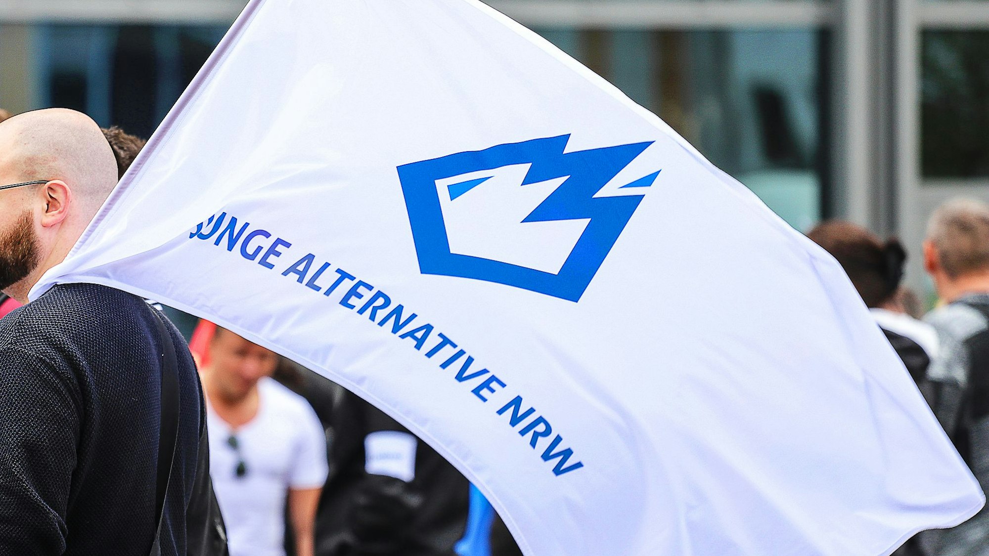 Ein Mitglied der «Jungen Alternative» (JA), Jugendorganisation der AfD, trägt auf einer Wahlkampfveranstaltung eine Fahne mit dem Logo der Organisation.