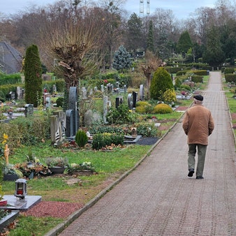 Ein Mann geht über einen Friedhof.