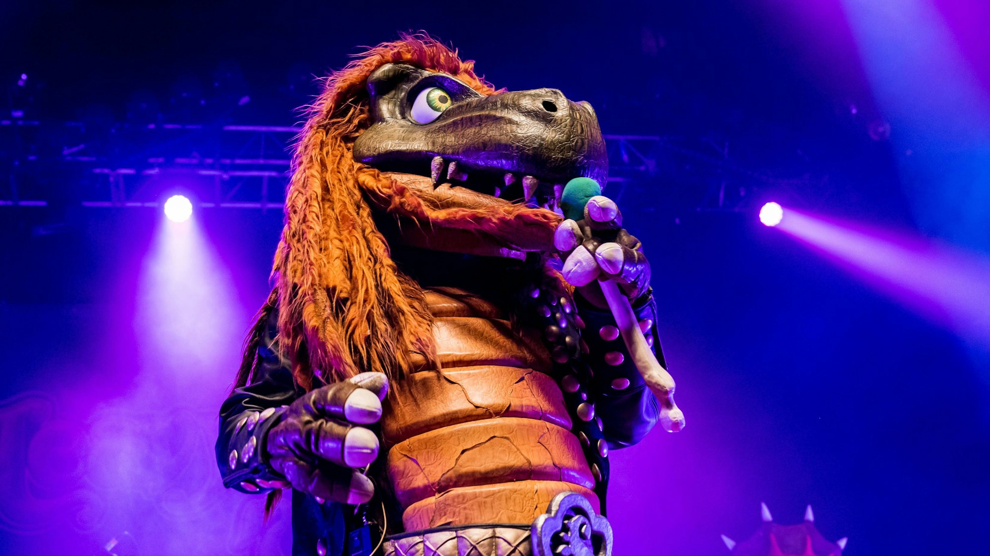 Musiker in Dinosaurierkostüm auf der Bühne.