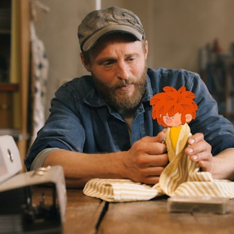 Florian Eder (Florian Brückner) wickelt den traurig schauenden Pumuckl in ein Tuch ein.