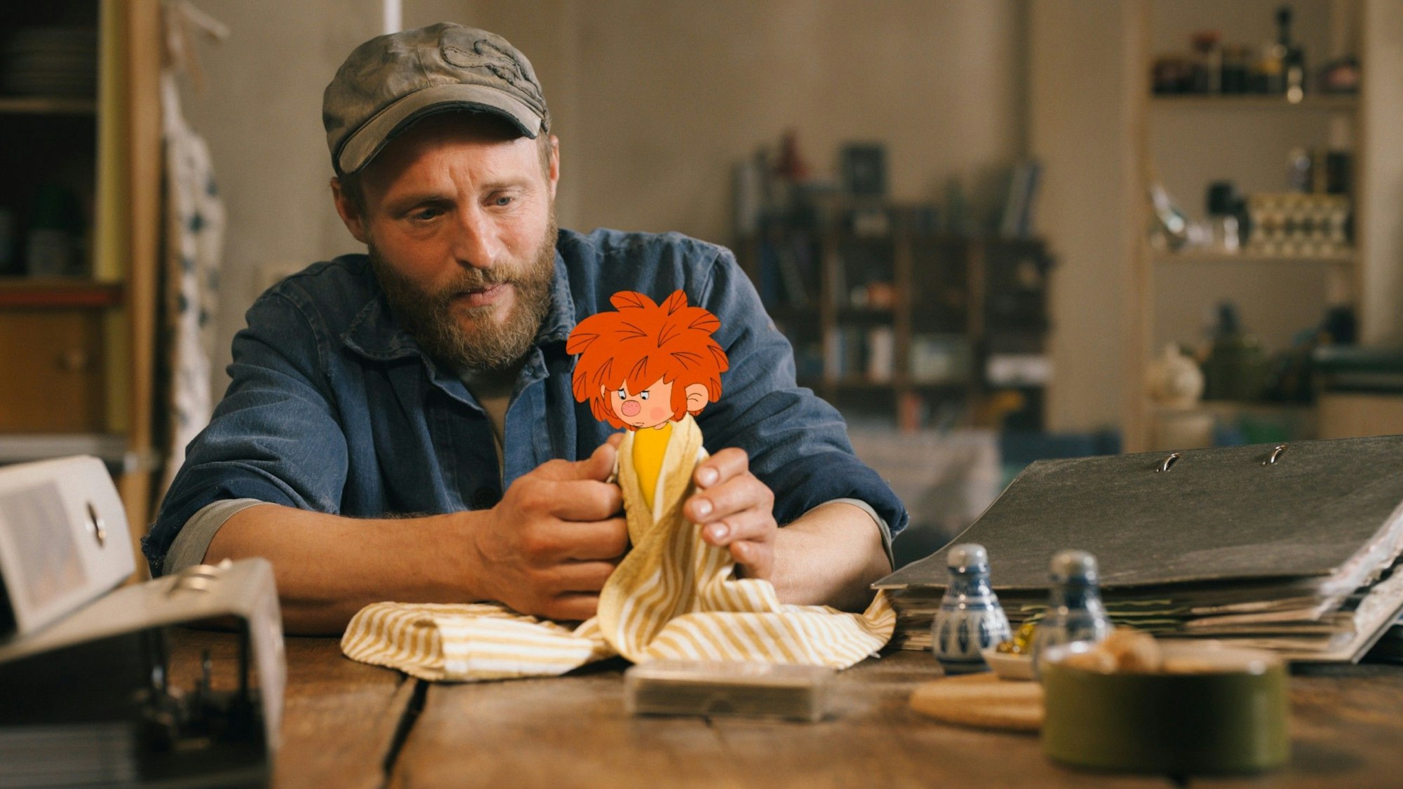 Florian Eder (Florian Brückner) wickelt den traurig schauenden Pumuckl in ein Tuch ein.