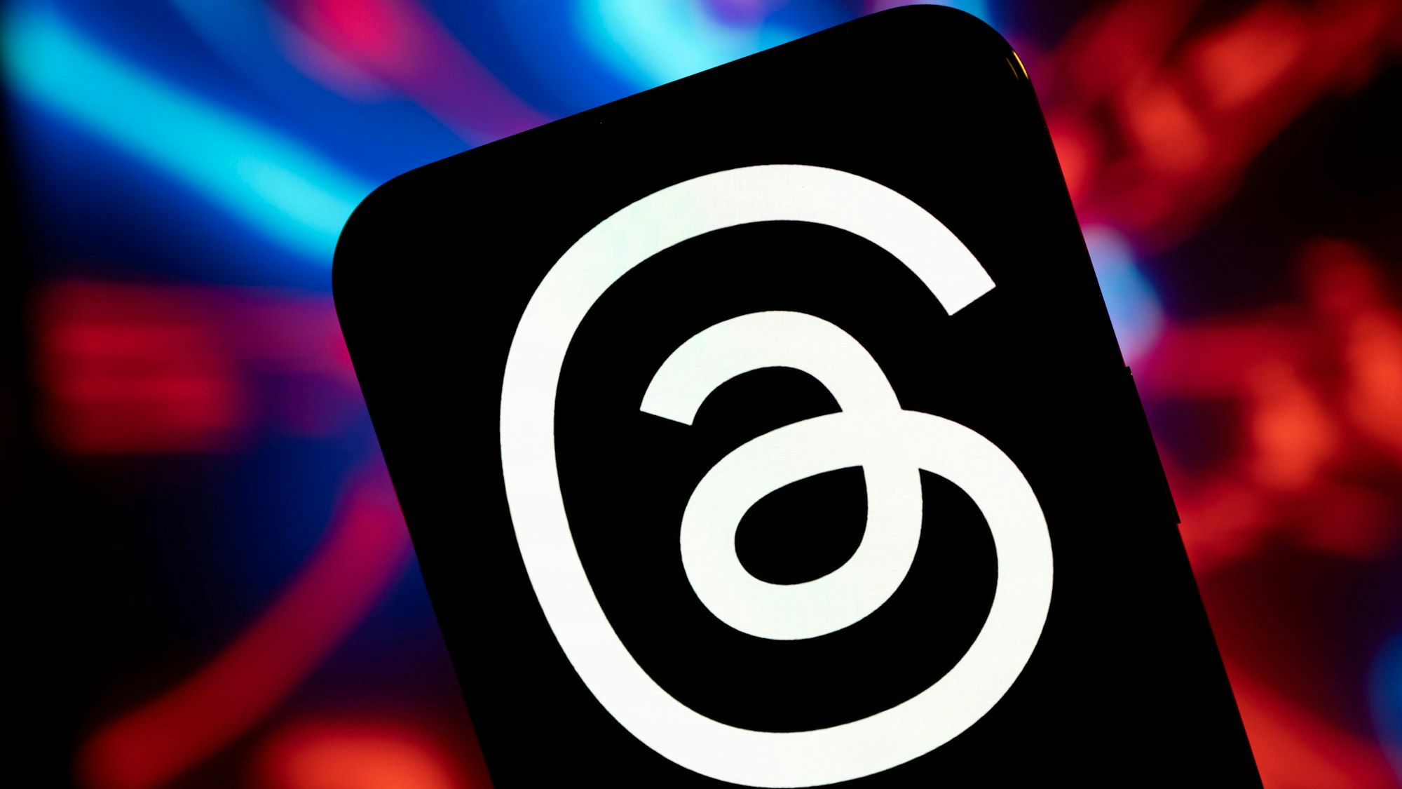 Das Logo von Threads. Ein weißer Faden auf schwarzem Grund.