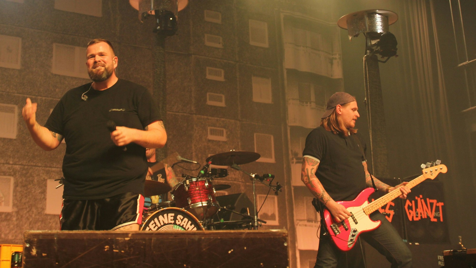 Das Bühnenbild zeigt die Fassade eines Plattenbaus. Davor stehen die Musiker der Band Feine Sahne Fischfilet.