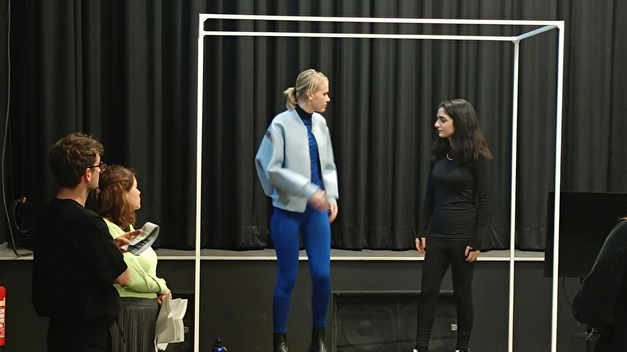 Zu sehen sind zwei der Darsteller bei der Probe auf der Bühne.