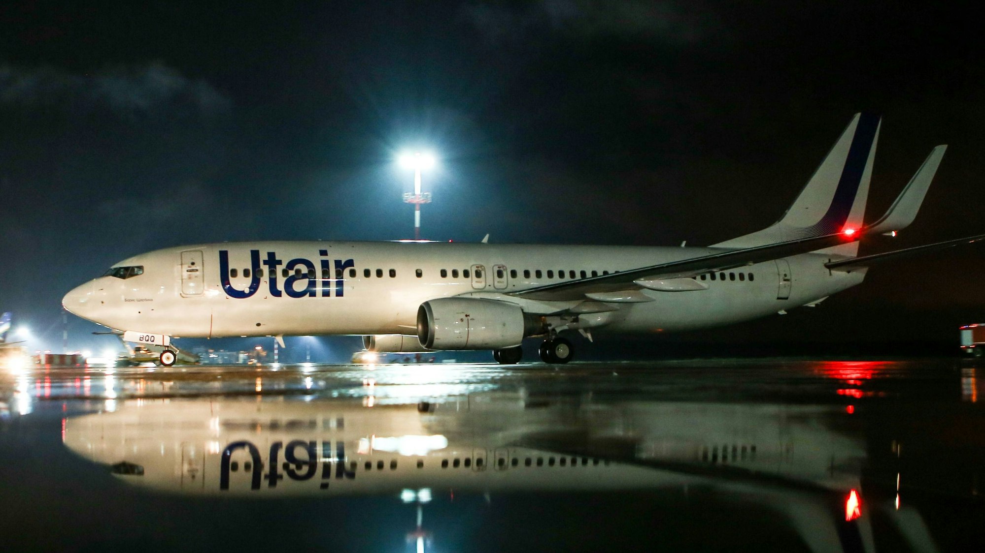 Eine Boeing 737 der russischen Fluggesellschaft UTair steht unter einem großen Scheinwerfer auf einem Rollfeld. Die Warnleuchte an den Tragflächen leuchtet. (Symbolbild)