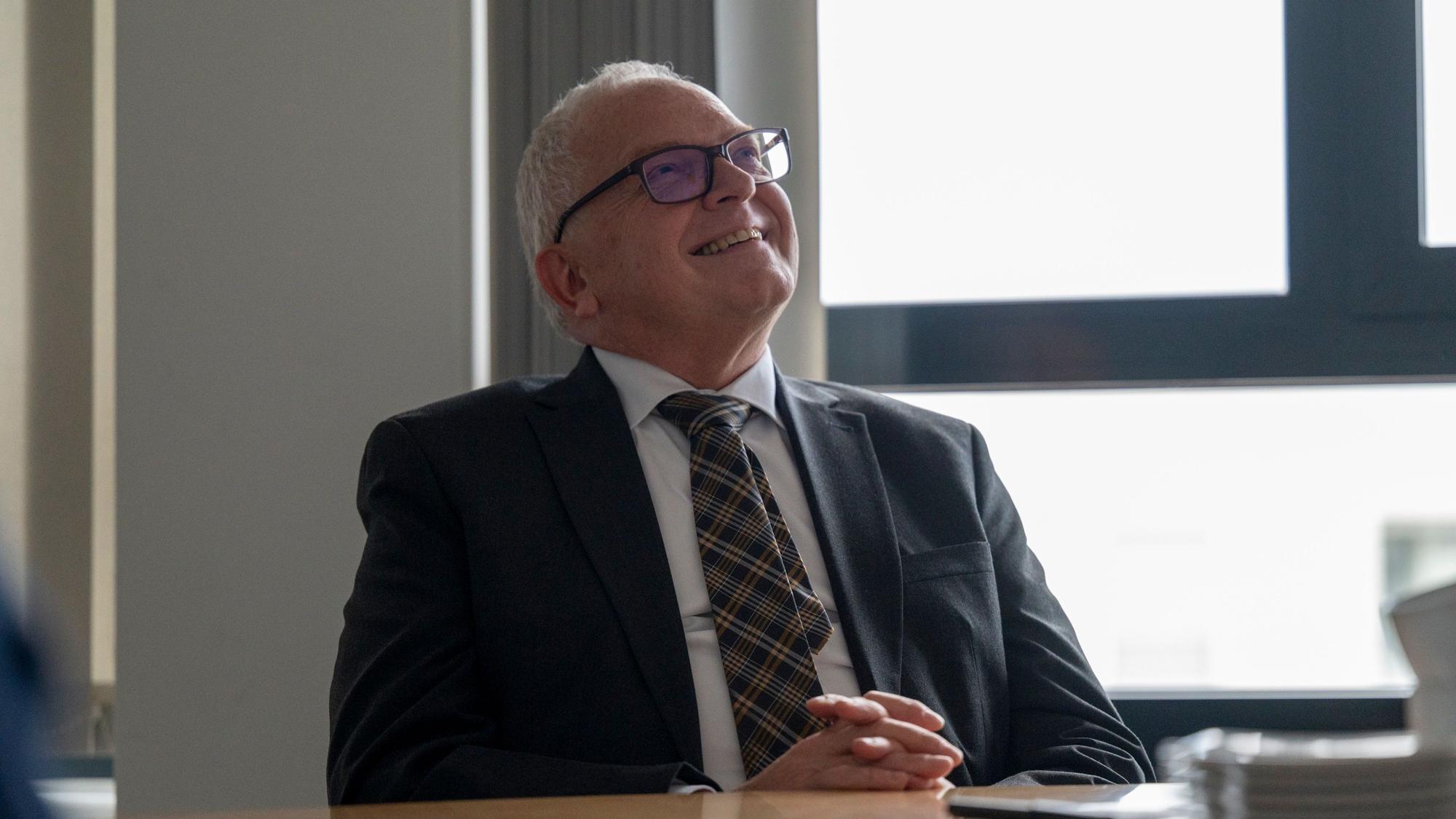 Johannes Hermanns sitzt an einem Besprechungstisch.