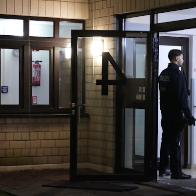 Ein Polizist steht vor einem Hauseingang.