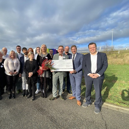 Die Mitglieder des Queeren Stammtischs Euskirchen stehen gemeinsam mit Euskirchens Bürgermeister und Landrat Markus Ramers vor ihrem Wagen mit Regenbogenflagge.