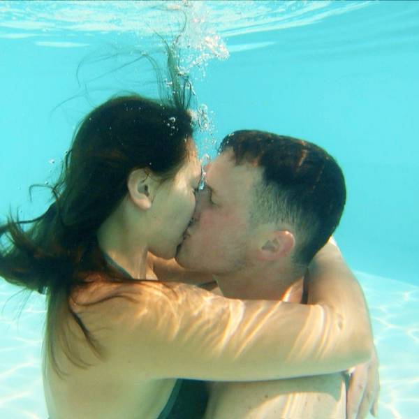 Ein junger Mann und eine junge Frau küssen sich unter Wasser in einem Swimmingpool.