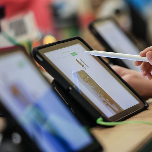 Ein Kind sitzt mit einem Stift vor einem iPad.