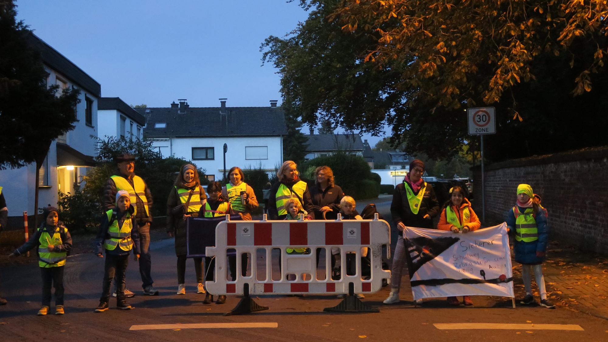 Eltern und Kinder sperren eine Straße.