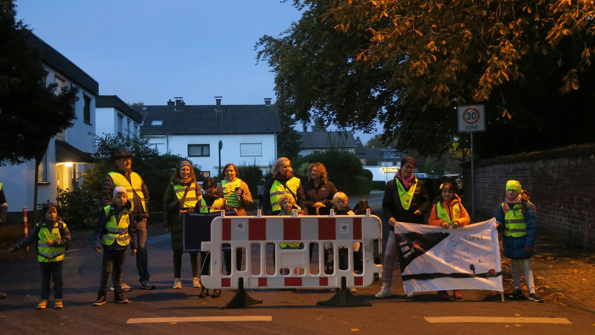 Eltern und Kinder sperren eine Straße.