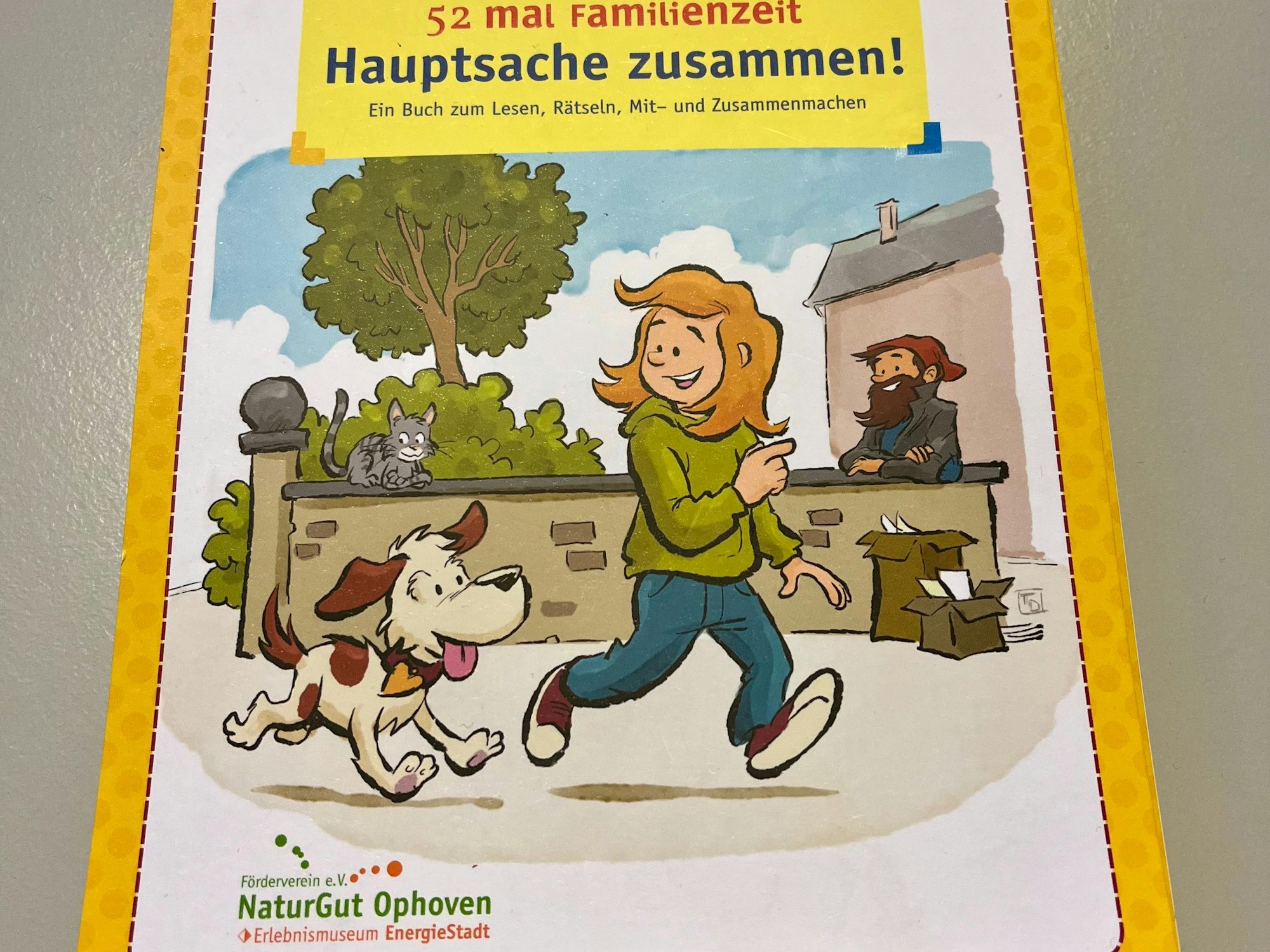 Ein Buch-Cover ist zu sehen. Ein Mädchen läuft mit einem Hund eine Straße entlang.