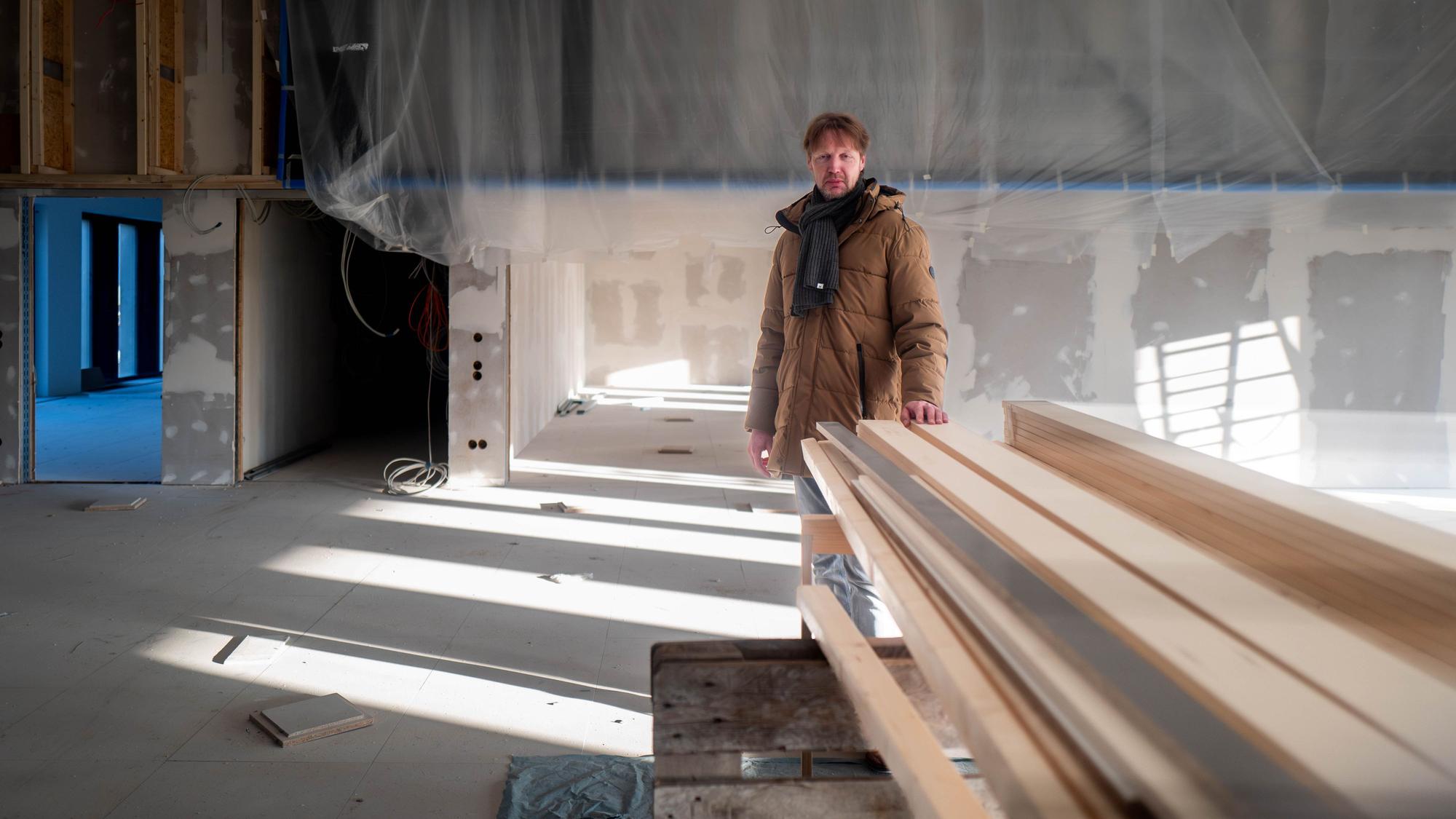 Das Bild zeigt Carsten Opitz hinter einem Stapel Holz, auf den er die linke Hand gelegt hat.