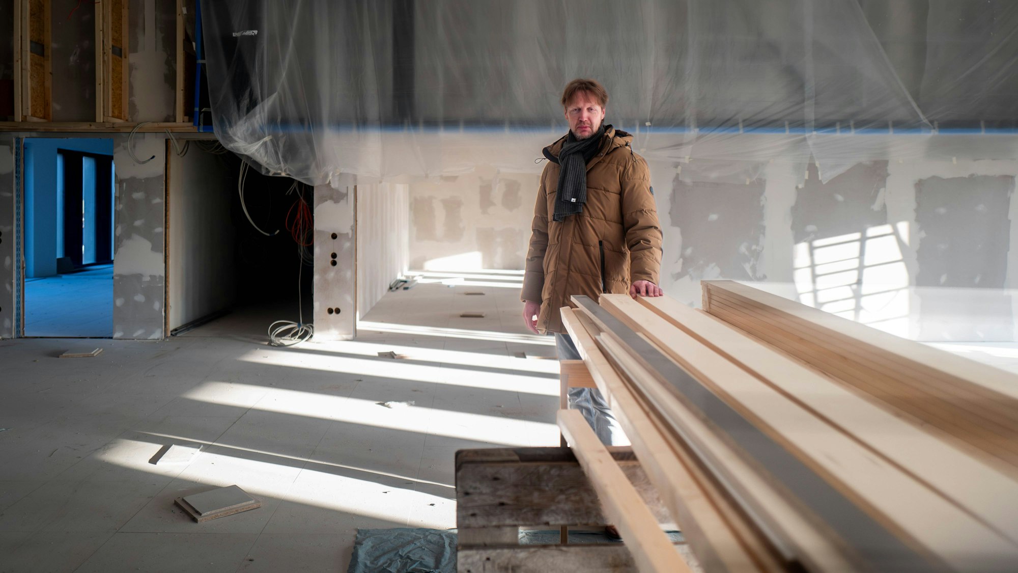 Das Bild zeigt Carsten Opitz hinter einem Stapel Holz, auf den er die linke Hand gelegt hat.