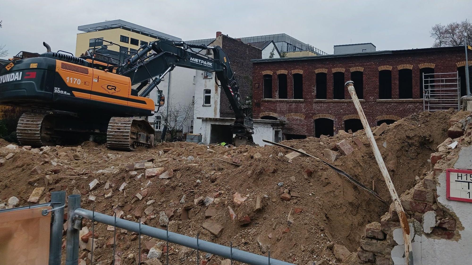 Ein orangefarbener Bagger auf einem Schuttberg auf einer Abbruchbaustelle