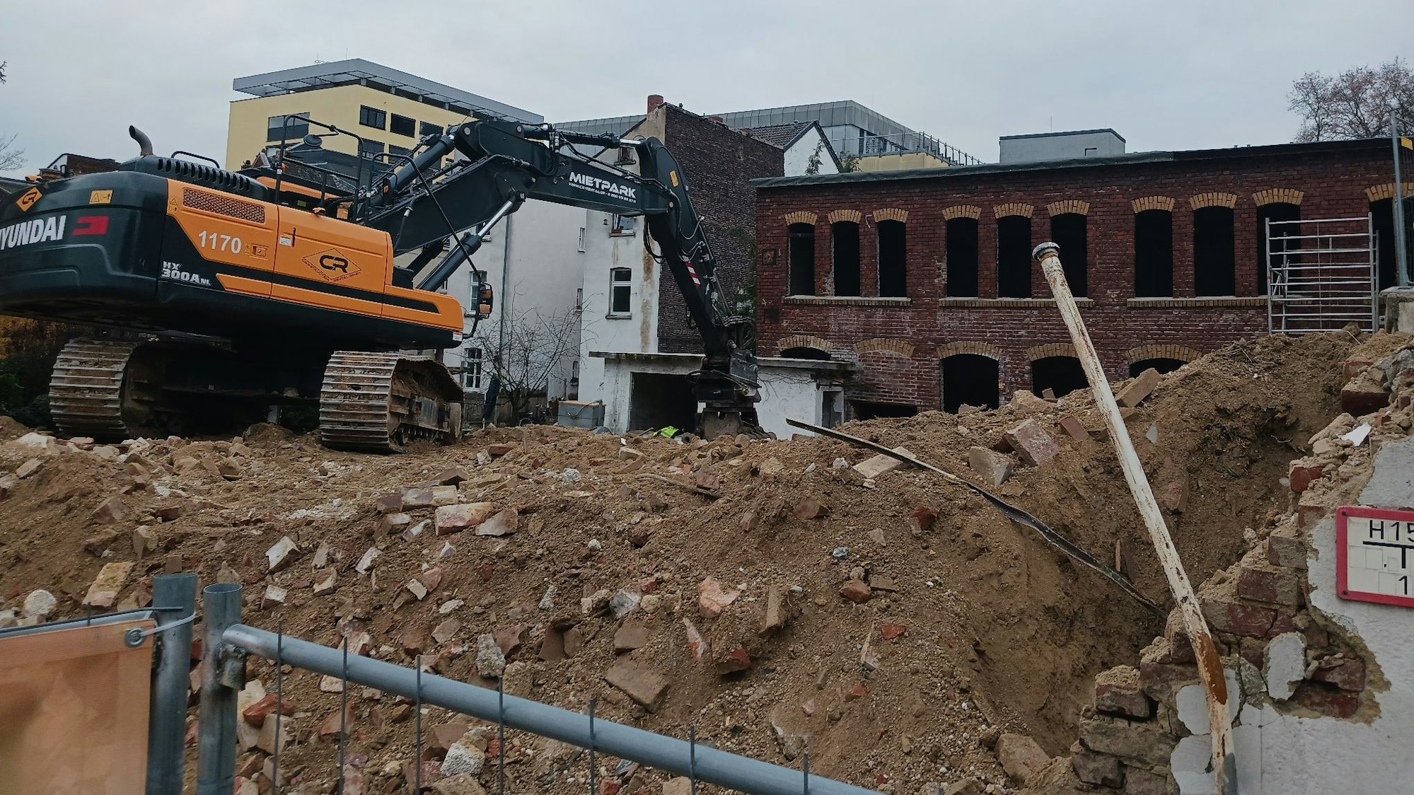 Ein orangefarbener Bagger auf einem Schuttberg auf einer Abbruchbaustelle