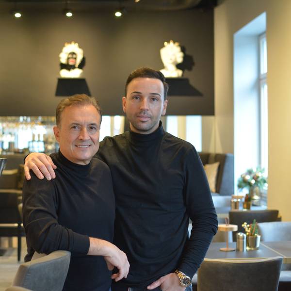 Zwei Männer stehen gemeinsam in einem Restaurant und schauen in die Kamera.