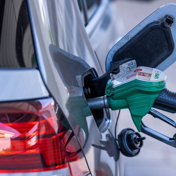 Eine Zapfpistole steckt an einer Tankstelle im Tankstutzen eines Autos.