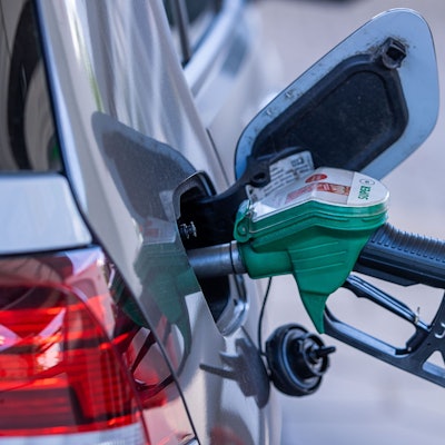 Eine Zapfpistole steckt an einer Tankstelle im Tankstutzen eines Autos.