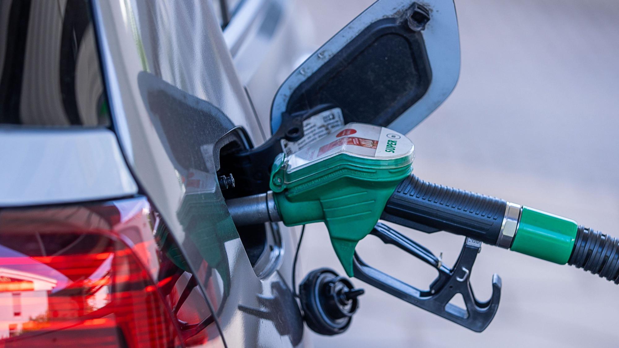 Eine Zapfpistole steckt an einer Tankstelle im Tankstutzen eines Autos.