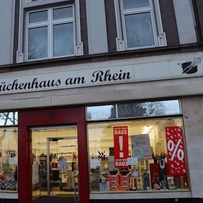 Eine Ladenzeile mit zwei großen Schaufenstern in einem historischen Gebäude.