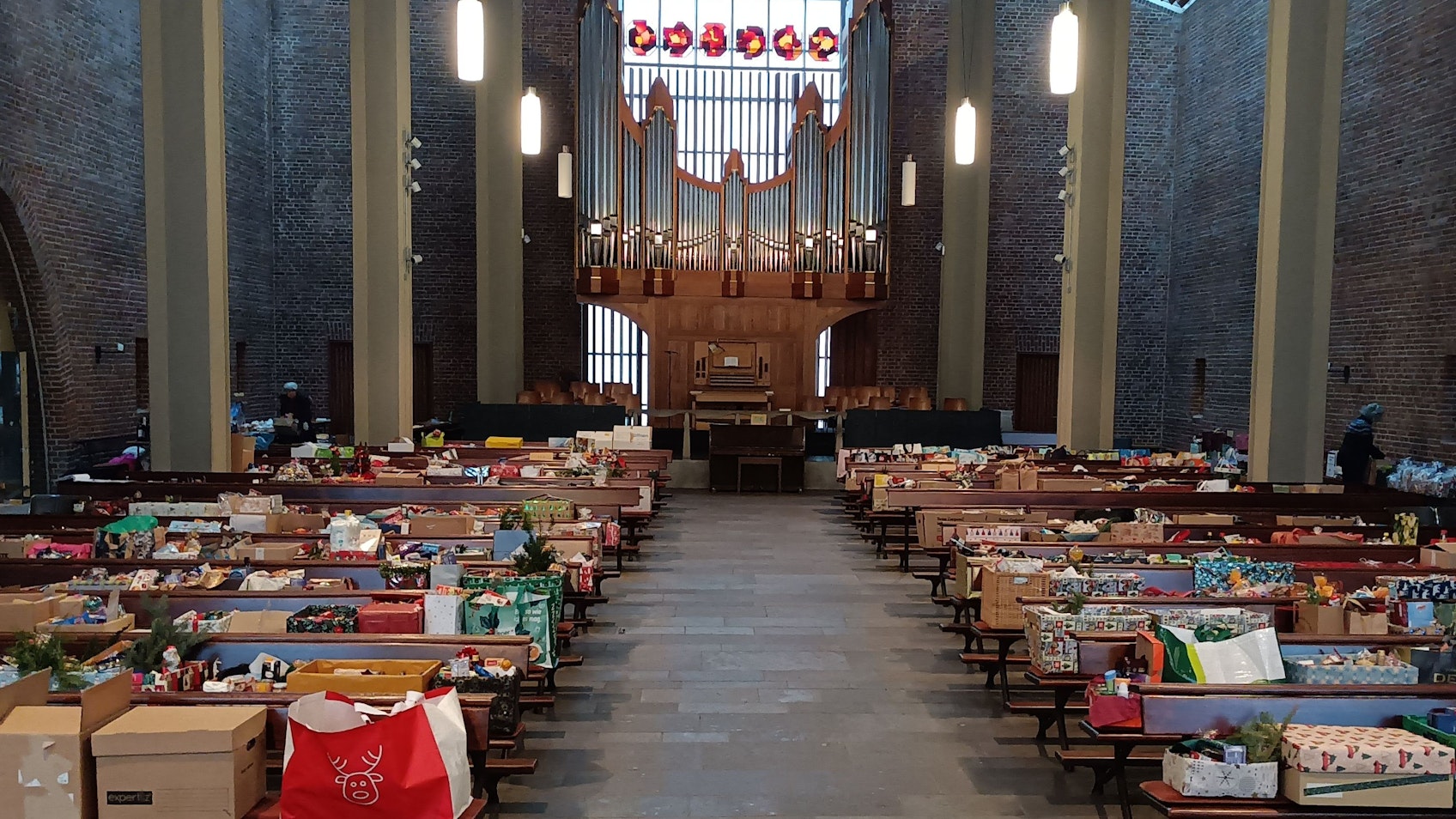 Kartons mit Geschenken liegen auf Kirchenbänken.