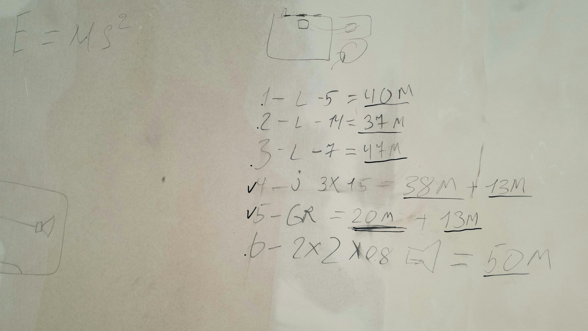 Das Bild zeigt zahlreiche Zahlen und Buchstaben, die mit einem Bleistift an die Wand geschrieben worden sind.