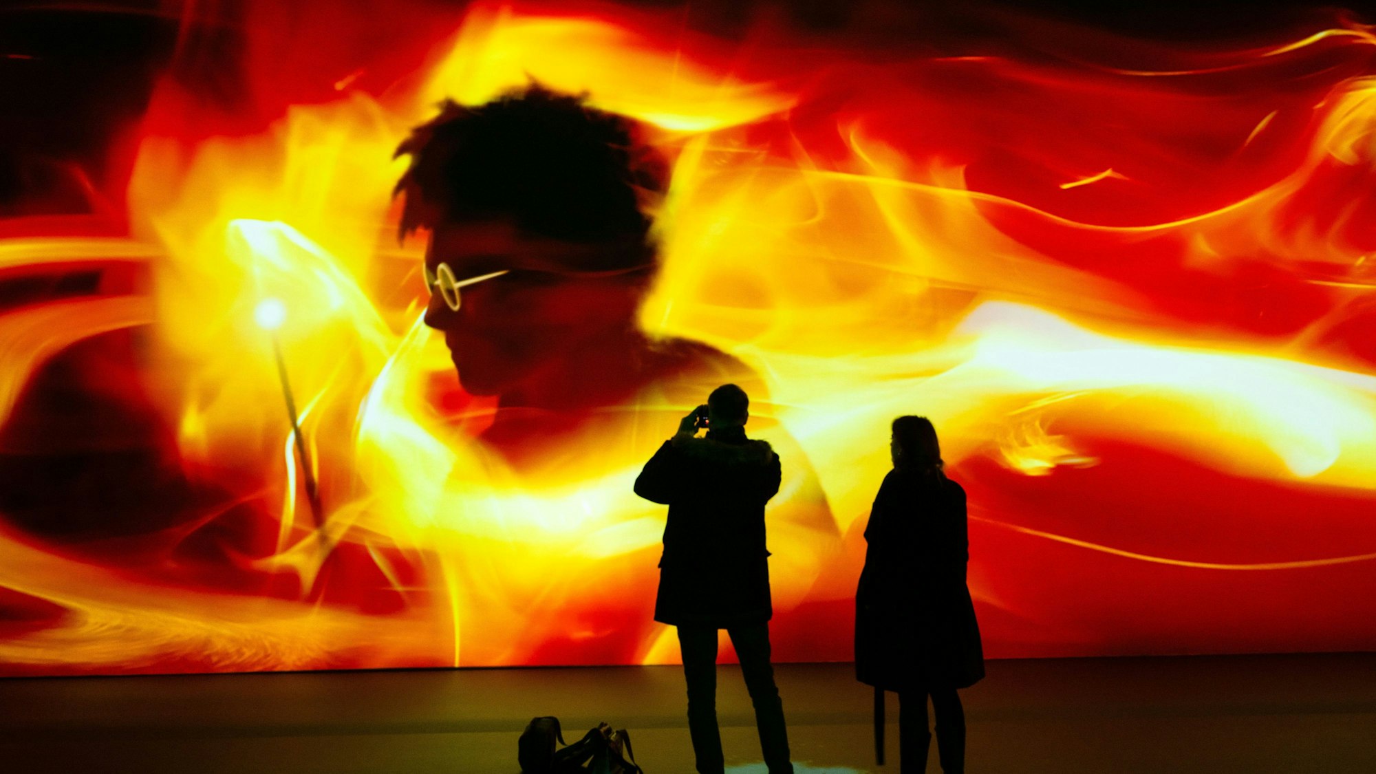 Auf einer Leinwand ist der Schatten von Harry Potter in roten Farbwirbeln zu sehen.