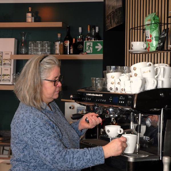 Eine Frau steht an einer Kaffeemaschine.