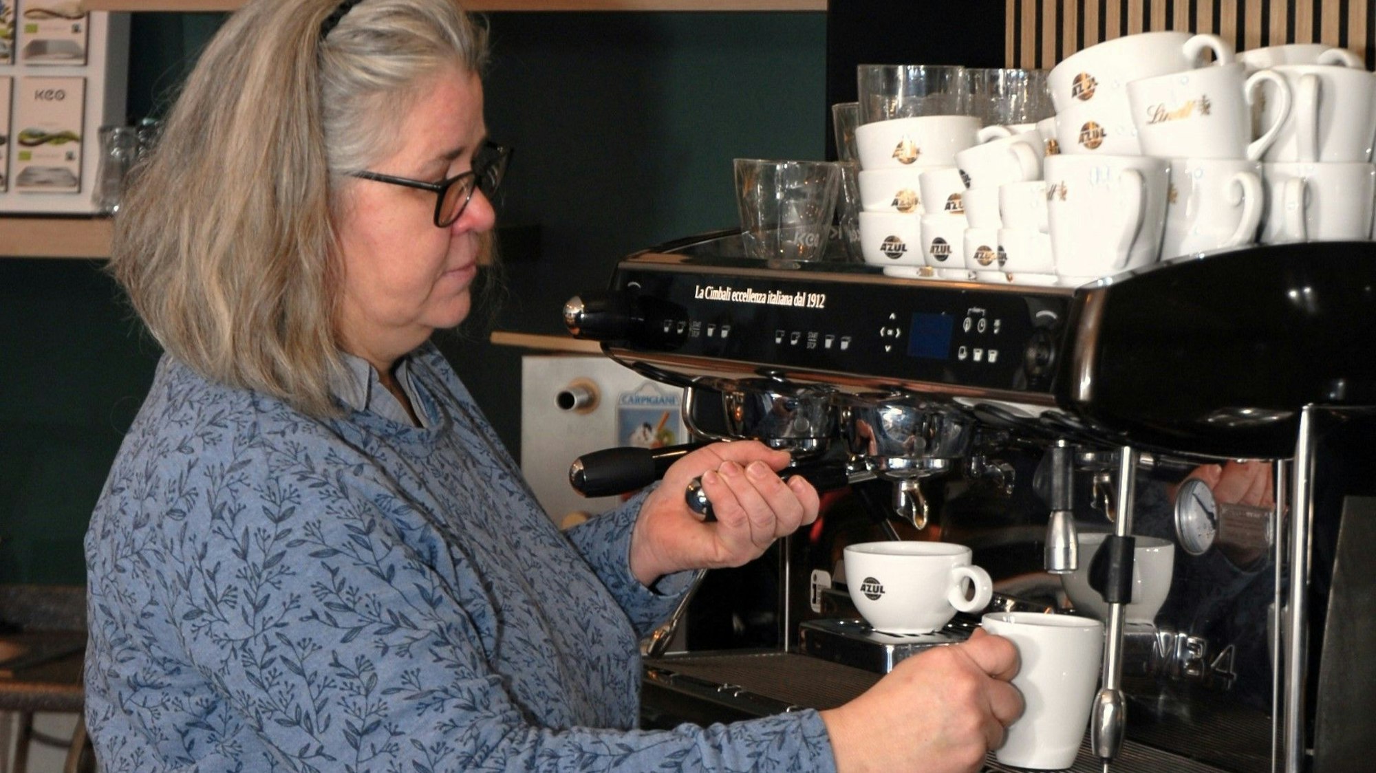 Eine Frau steht an einer Kaffeemaschine.
