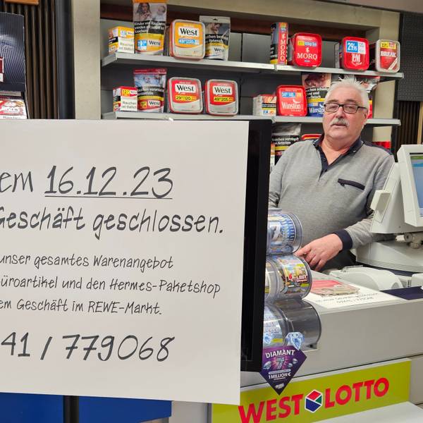 Hans-Dieter Pütz steht hinter einem Schild, das die Schließung des Geschäfts ankündigt, am Tresen.