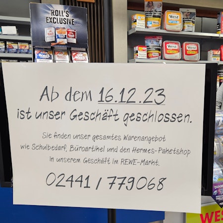 Hans-Dieter Pütz steht hinter einem Schild, das die Schließung des Geschäfts ankündigt, am Tresen.